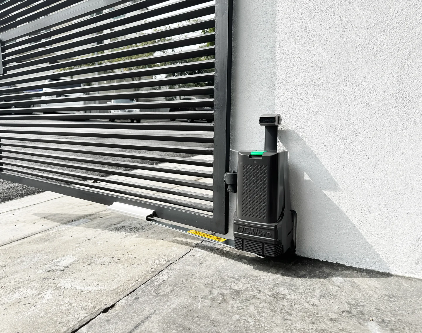 DCMoto motor and operating arm fitted to a horizontal metal gate beside a white wall