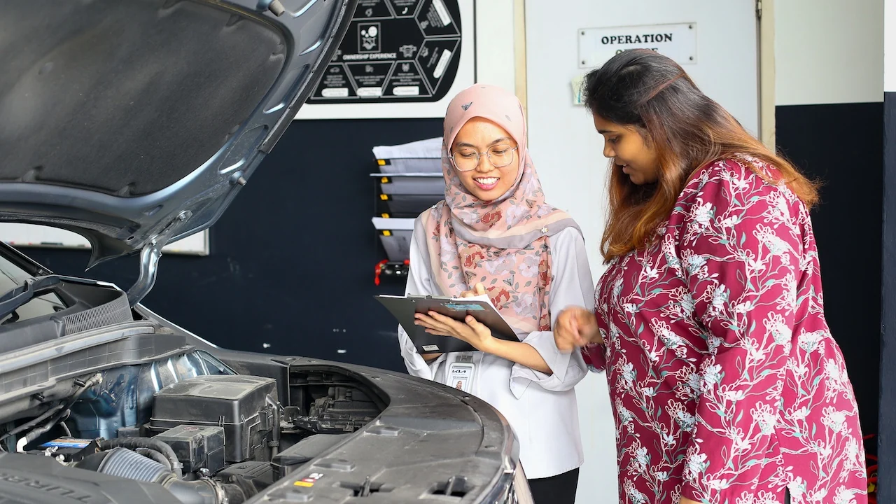 Kia Puchong workshop photograph showing a discussion beside a vehicle with its bonnet open