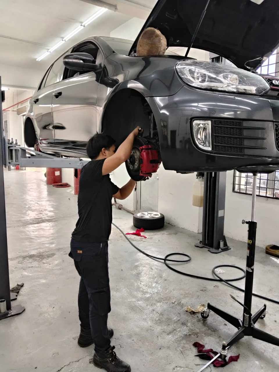 Juruteknik Toyokar menjalankan kerja pembaikan di sisi kenderaan yang diangkat menggunakan lif bengkel